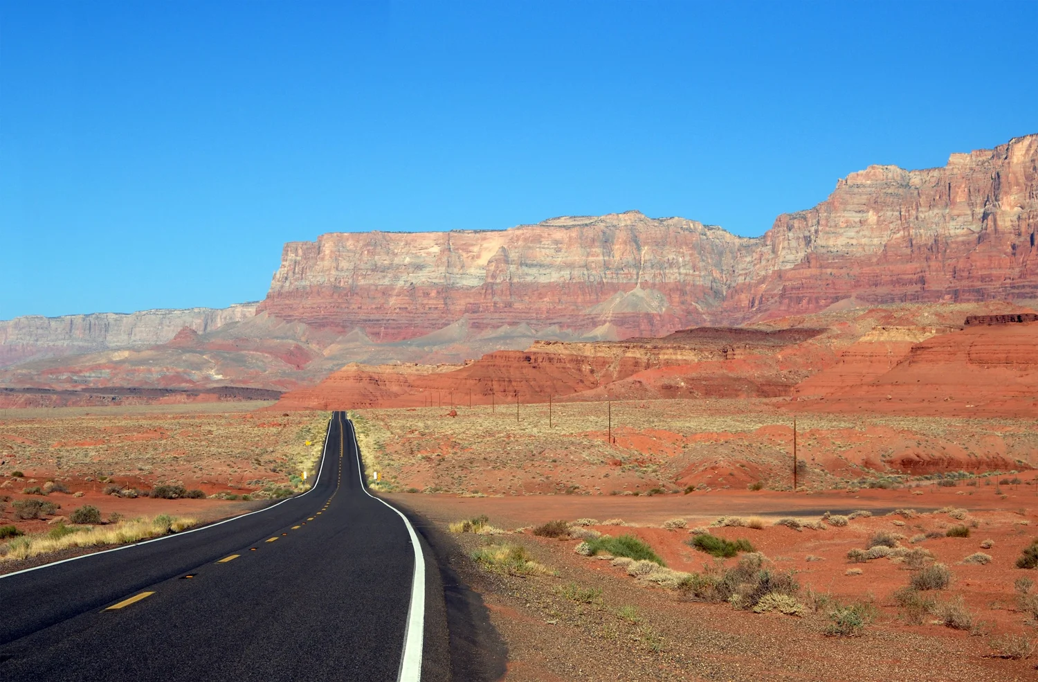 A road leading through a desert canyon beneath a blue sky